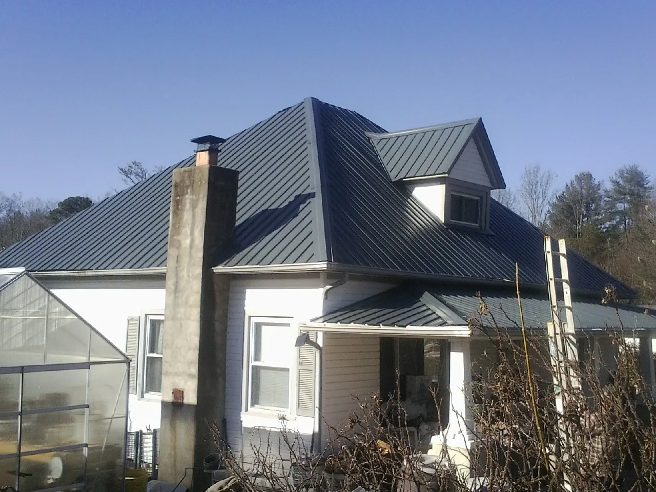 Dark blue standing seam metal roof on a white farmhouse with dormer — Slate & Tile Roof Repair by Roofing Brothers in Eugene