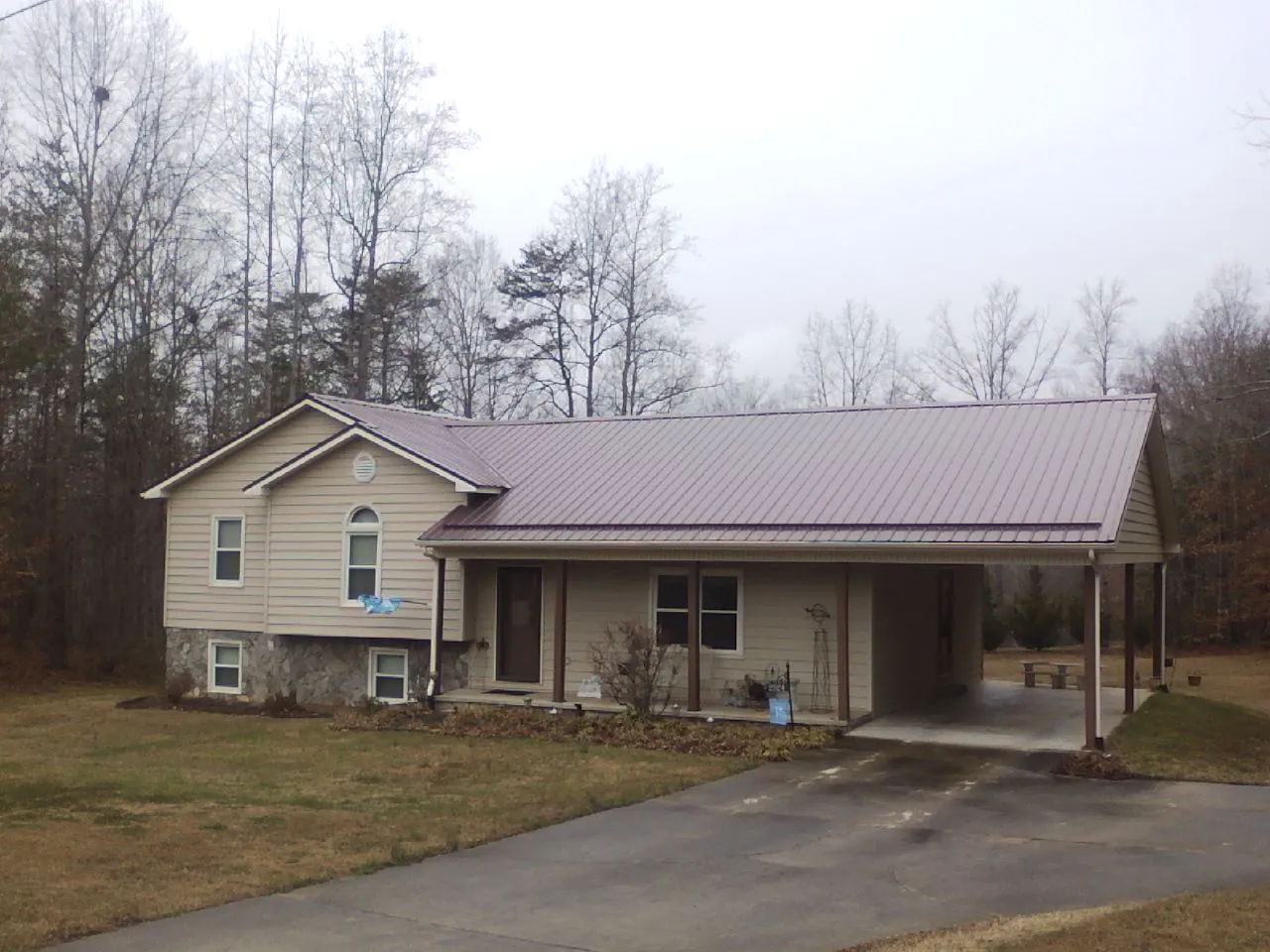 Burgundy metal roof on a tan split level home with an attached carport in Eugene