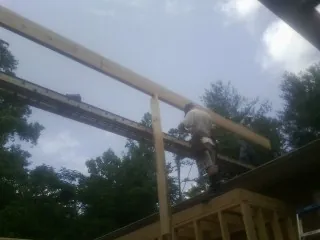 Carpenter setting a ridge beam over a new addition frame — Ice Dam Removal by Roofing Brothers in Eugene
