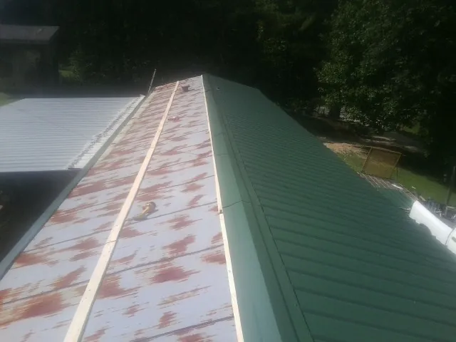 Old rusted panels beside newly installed green metal roofing — Wind Damage Roof Repair by Roofing Brothers in Eugene