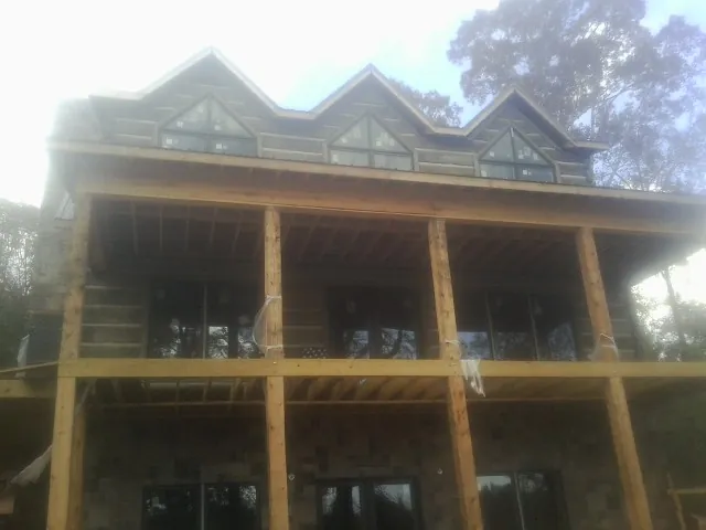 Dormers and porch framing on a large log home under construction — Roof Coating work by our crew in Eugene