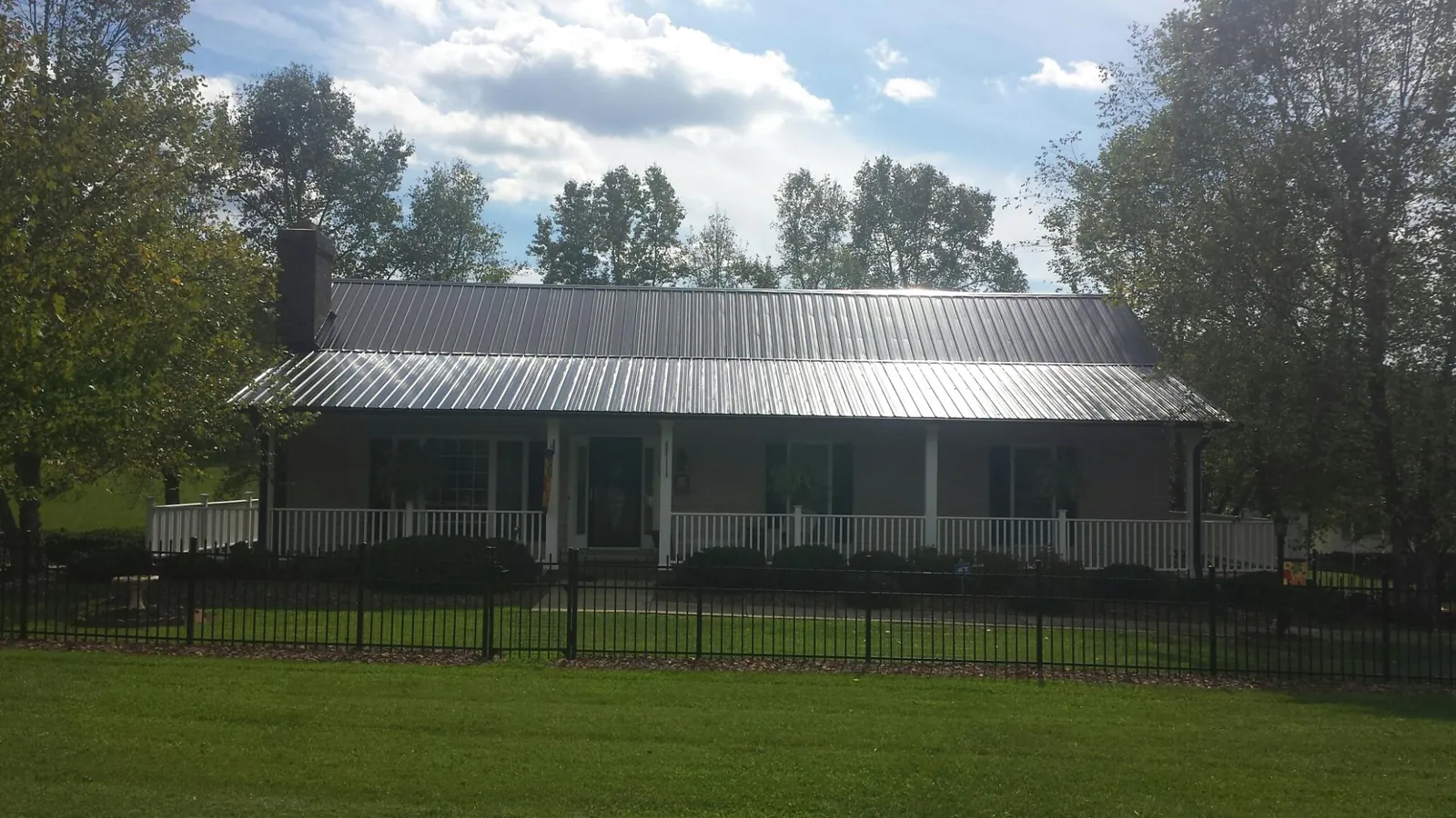 Gray metal roof on a brick ranch with a full width front porch — Gutter Guard Installation work by our crew in Eugene