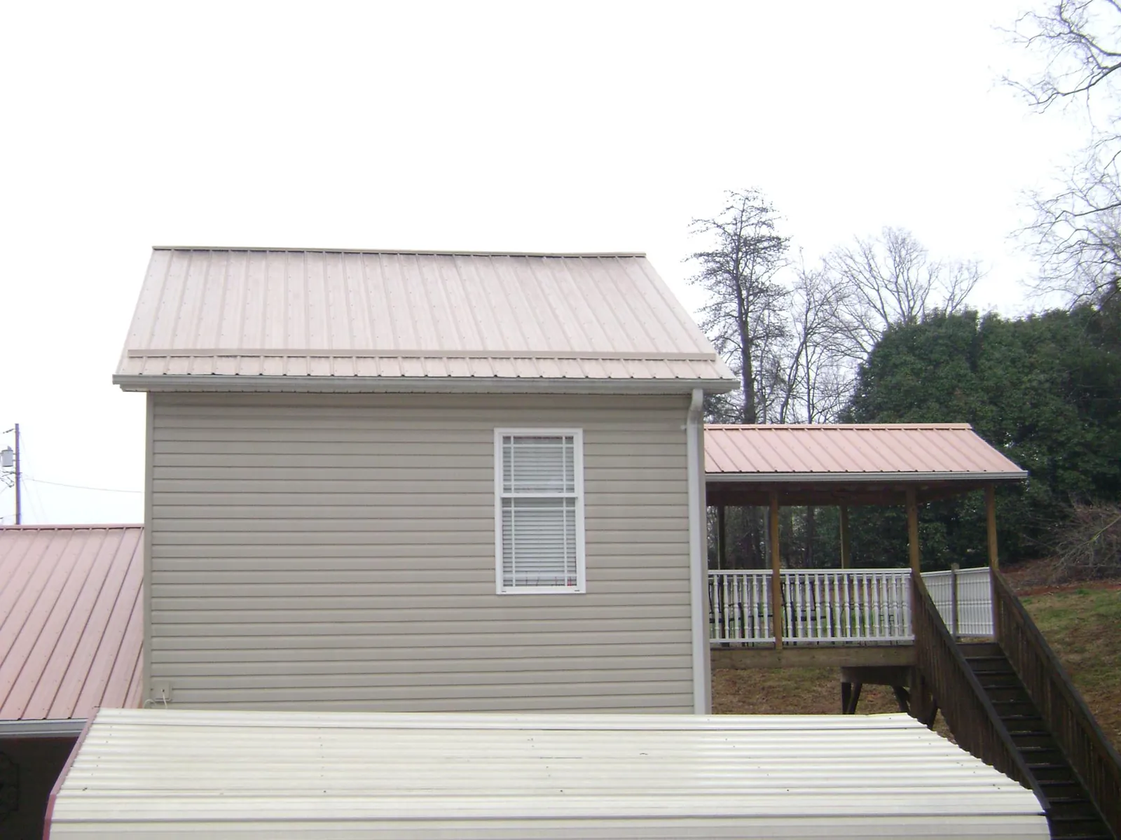 Tan metal roofs on a two story addition and attached porch, from a Roof Replacement job in Eugene