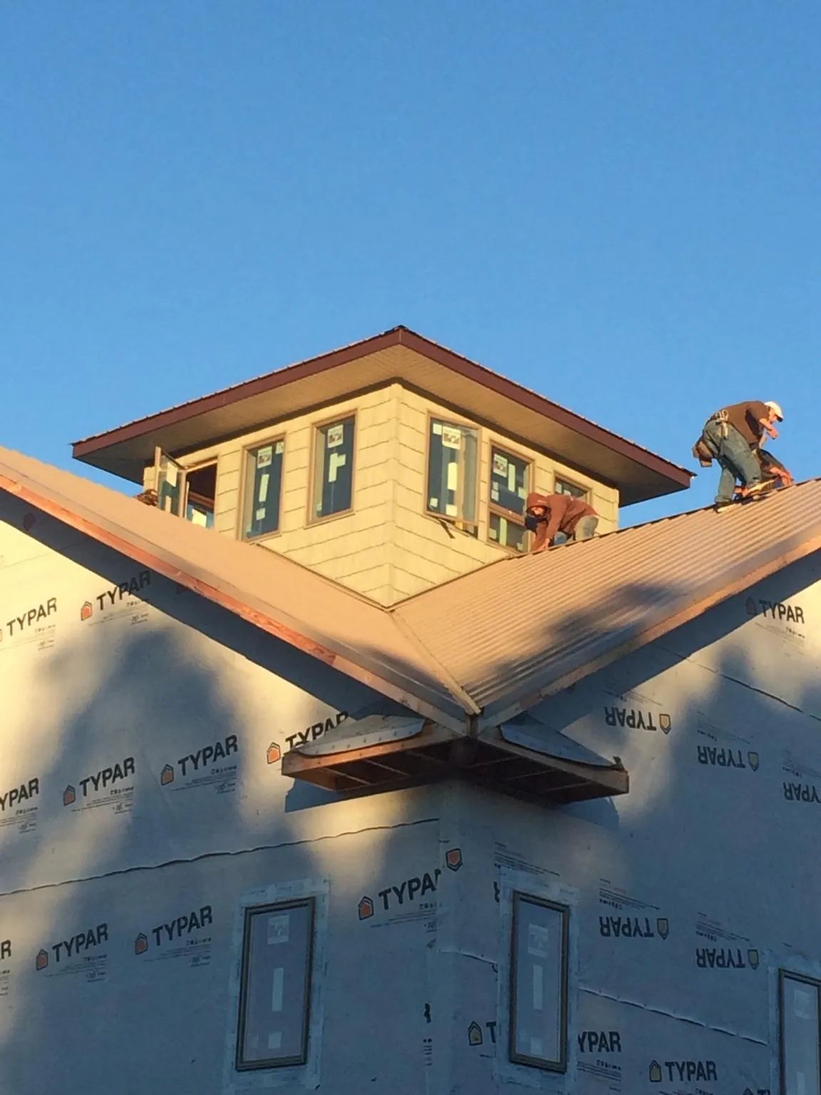 Roofers working around a rooftop cupola on a new metal roof at sunset — Roof Waterproofing in Eugene by Roofing Brothers